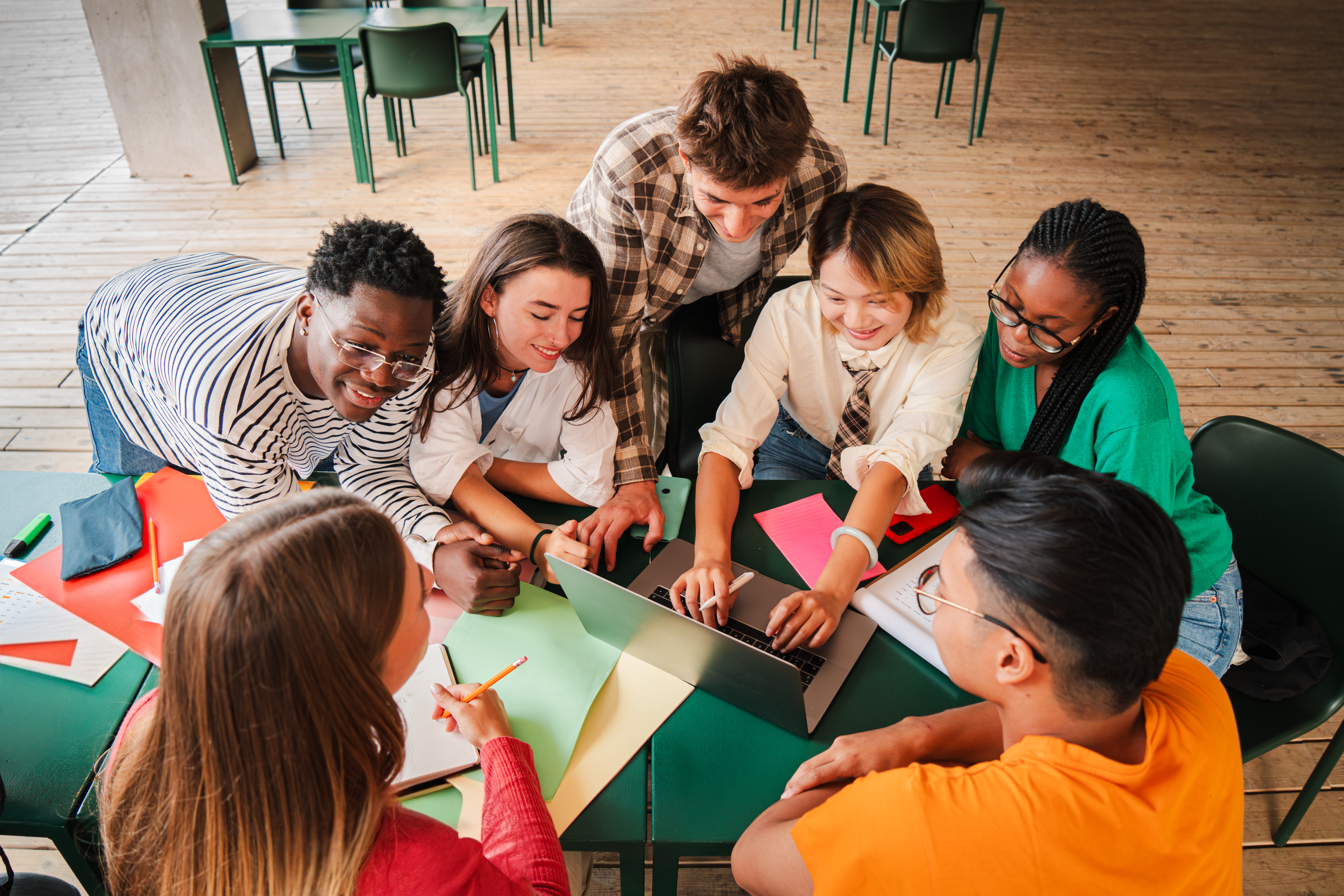 diverse group of youth working around a table with a laptop